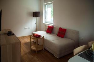 a living room with a couch with two red pillows at Chang Thai apartments in Ljubljana