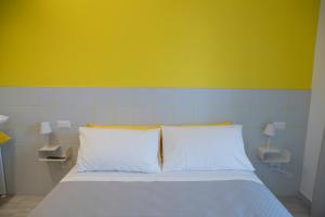uma cama com duas almofadas brancas e uma parede amarela em Marigold Residence em Roseto degli Abruzzi