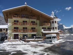 ein großes Gebäude mit einem davor geparkt in der Unterkunft Hotel Ciamol in Mazzin