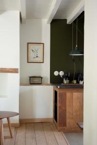 une cuisine avec des murs verts et blancs et une table dans l'établissement Le Roitelet - Suite d'hôtes privative, à Montcavrel