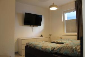 a bedroom with a bed with a flat screen tv on the wall at Apartment Hanske in Isenbüttel