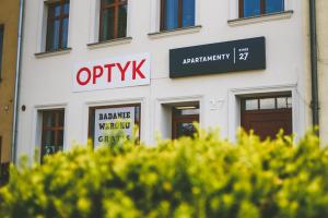 a white building with a sign that reads optix at Apartamenty Rynek 27 in Prószków