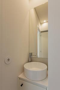 a white bathroom with a sink and a mirror at ORM Antero Apartment in Porto