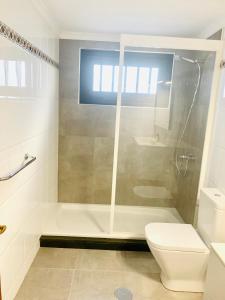 een witte badkamer met een douche en een toilet bij Tagoror Lanzarote in Puerto del Carmen