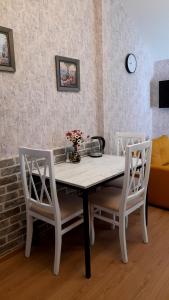 einen Esstisch mit zwei weißen Stühlen und einem Sofa in der Unterkunft Yellow Apartment in Tbilisi City