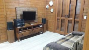 um quarto com uma televisão e uma cama e uma banca de televisão em Casa Aconchegante Praia do Rosa Ibiraquera SC em Imbituba