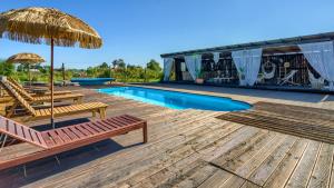 a deck with chairs and an umbrella and a pool at pod mazurskim niebem loft in Piecki