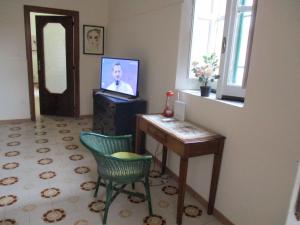 uma sala de estar com uma televisão e uma mesa e cadeiras em Giardino degli aranci - Resort em Baronissi