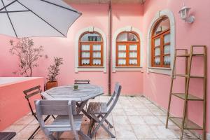 a patio with a table and chairs and a pink wall at Praça Guest House in Arouca