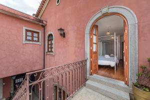 a pink house with a balcony with a bedroom at Praça Guest House in Arouca