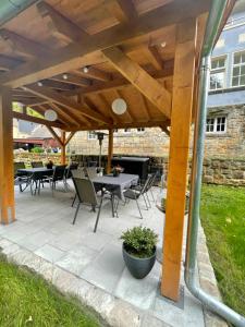 a patio with tables and chairs under a wooden roof at Ferienwohnung Sächsische Schweiz in Bielatal