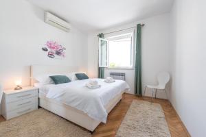 a white bedroom with a white bed and a window at Villa Markoc in Cavtat