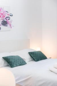 Una cama blanca con almohadas verdes y flores. en Villa Markoc, en Cavtat