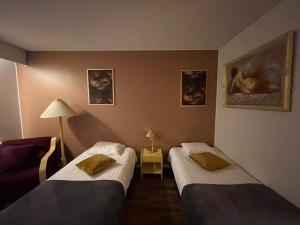 Zimmer mit 2 Betten, einer Lampe und Gemälden in der Unterkunft hotelli ravintola kurenkoski in Pudasjärvi + 8 Fotos