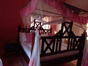 a bedroom with a wooden bed with a canopy at Roseville in Diani Beach
