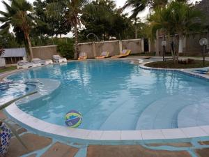 a large swimming pool with chairs and palm trees at Roseville in Diani Beach
