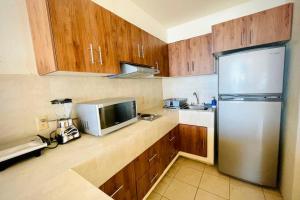 a kitchen with wooden cabinets and a stainless steel refrigerator at Espectacular Apto a pie de Playa con vista al mar in Manzanillo