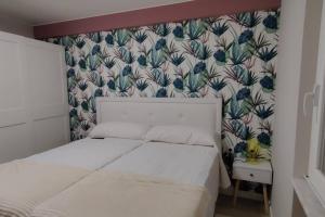 a bedroom with a white bed and a floral wallpaper at Los Sitios in Astorga