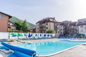 a large swimming pool with blue chairs and umbrellas at Studio Anastasia in Sapareva Banya