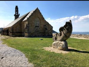 a stone statue in front of an old church at LISACA in Camaret-sur-Mer