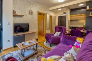 a living room with purple furniture and a tv at Apartman Enjoy in Zlatibor