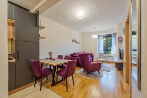 eine Küche und ein Esszimmer mit einem Tisch und lila Stühlen in der Unterkunft Apartman Enjoy in Zlatibor