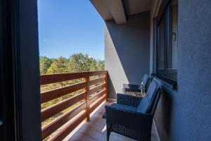 einen Balkon mit 2 Stühlen, einem Tisch und einem Fenster in der Unterkunft Apartman Enjoy in Zlatibor