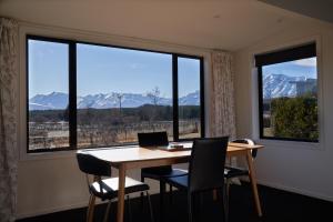 a dining room with a table and chairs and windows at Cass Crib - Lake Tekapo in Lake Tekapo