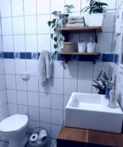 y baño con aseo blanco y lavamanos. en Quarto em casa compartilhada, en Florianópolis