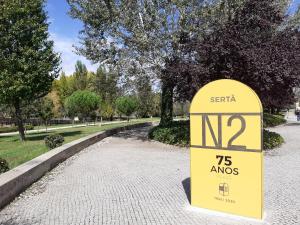 a yellow sign sitting on a sidewalk in a park at Largo da Fonte in Sertã