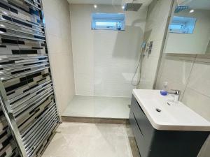 y baño blanco con lavabo y ducha. en NEW MODERN STUDIO APARTMENT, PARKING, Netflix, en Kenilworth