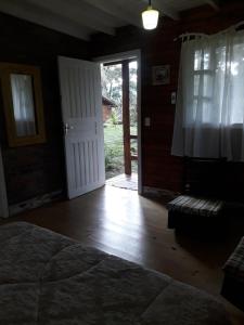 1 dormitorio con 1 cama y puerta abierta en Cabanas El Polista, en Canela