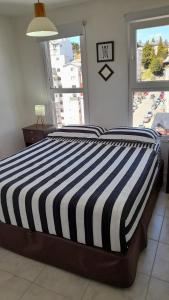 a bedroom with a striped bed with a window at Bariloche Modern Apartment in San Carlos de Bariloche