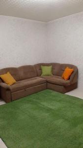 a living room with a brown couch and a green rug at Apartments at Laureatov 43 in Noril'sk