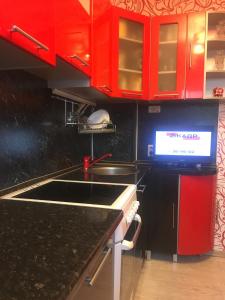 a kitchen with red cabinets and a sink at Apartments at Laureatov 43 in Noril'sk