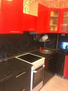 una cocina con armarios rojos y fregadero en Apartments at Laureatov 43 en Norilsk