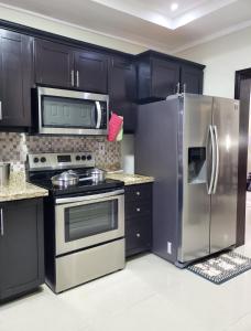 une cuisine avec armoires noires et appareils en acier inoxydable dans l'établissement Maison Romantique, à Kingston