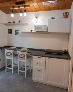 a kitchen with a counter with a microwave and stools at La Terrazza Azzurra in Bellisio di Sopra