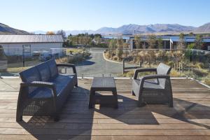 a patio with two benches and a table and a view at Bivouac - Lake Tekapo in Lake Tekapo