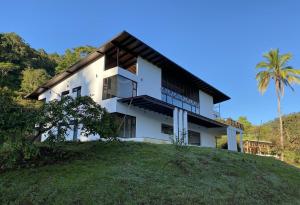 Arte de Plumas birding lodge في كرتاغو: منزل على تلة مع نخلة