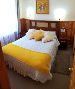 1 dormitorio con 1 cama grande con sábanas y almohadas amarillas en Depto Parque Suizo 800, en Pucón