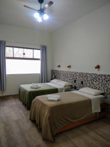 a bedroom with two beds and a window at Suítes da Eu Florinha in Carrancas