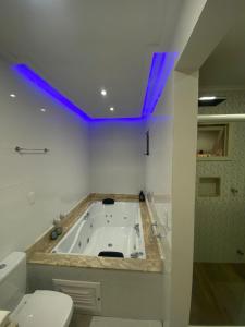 y baño con bañera con luces moradas. en Suíte da Cris em Gramado, en Gramado