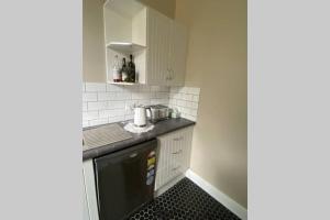 uma pequena cozinha com armários brancos e uma máquina de lavar louça preta em Kitty Spain's Cottage em Mannum