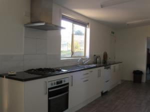 une cuisine avec des armoires blanches, un évier et une fenêtre dans l'établissement Delegate Nurses Cottage, à Delegate