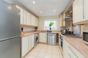 a kitchen with white cabinets and stainless steel appliances at Stunning Garden House with Free WIFI and Parking in Bingham