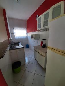 a small kitchen with a white and red wall at Vivamar2 in Cabo Frio