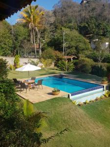 a swimming pool in a yard with a table and chairs at Belíssima Casa Sitio em Condomínio na Serra - Paty do Alferes in Paty do Alferes