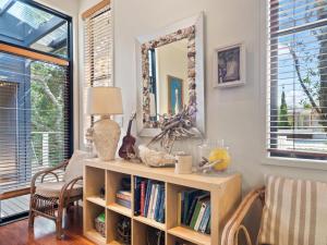 a living room with a mirror and a book shelf at Baleen Beach House by Discover Stradbroke in Point Lookout