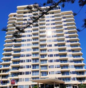 a tall white apartment building with an umbrella at Southern Cross Beachfront Holiday Apartments in Gold Coast